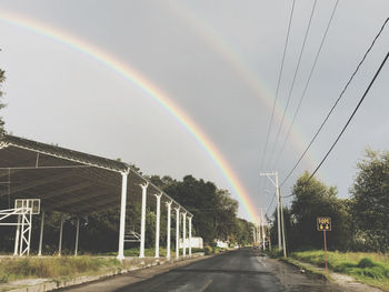Rainbow over road against sky