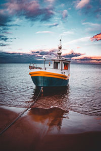 Boat moored on sea against sky during sunset