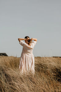 Young woman standing on field against clear sky