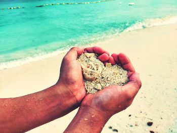 Midsection of person holding sand on beach