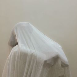Woman covered in textile against wall