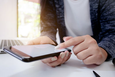 Midsection of man holding smart phone on table