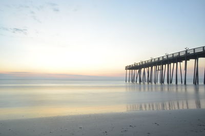 Pier over sea against sky during sunset