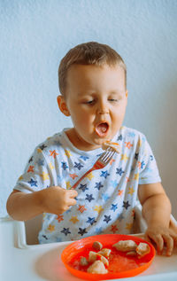 Close-up of cute boy eating food at home