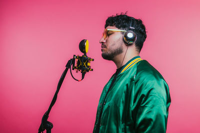 Side view of young man standing against yellow background