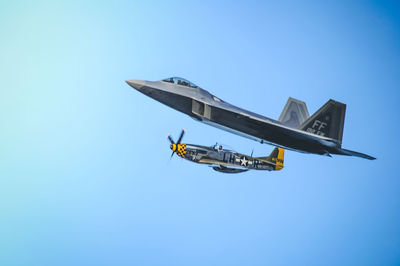 Low angle view of airplane flying against clear blue sky