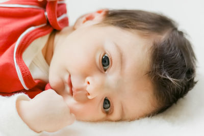 Portrait of cute baby girl lying on bed at home