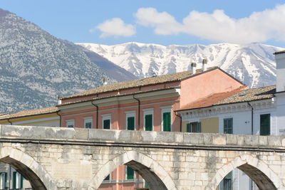 Arch bridge over snowcapped mountains against sky