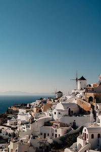 High angle view of townscape by sea against clear blue sky