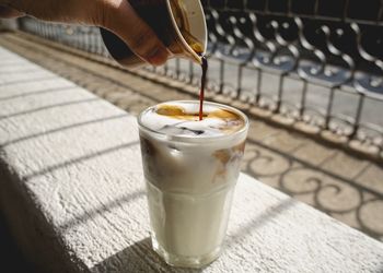 Close-up of person pouring coffee in drinking glass outdoors