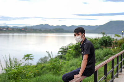 Young man looking at lake against mountain