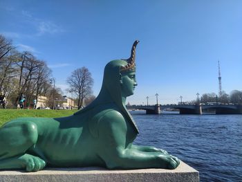 Statue by trees against blue sky