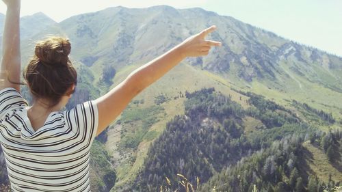 Woman with arms raised standing in front of mountains