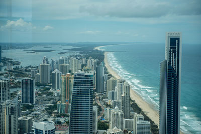 Aerial view of buildings by sea against sky