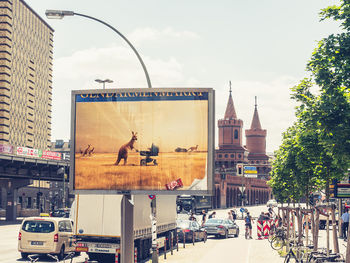 Vehicles on road by buildings in city against sky