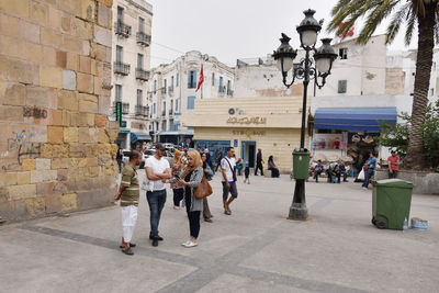 People walking on street amidst buildings in city