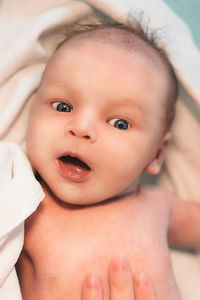 Close-up of toddler with gray eyes lying on bed