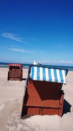 Hooded chairs on beach against sky