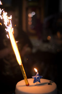 Close-up of hand holding lit candle