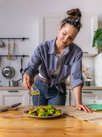 Young and beautiful housewife woman cooking in a white kitchen