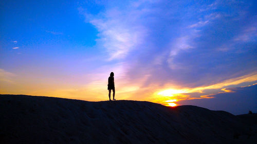 Silhouette man standing on mountain against sky during sunset