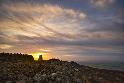 Rock formations on landscape against sky during sunset