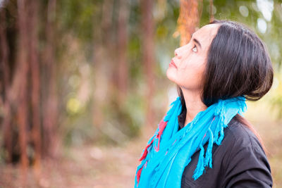 Woman looking up while standing in forest