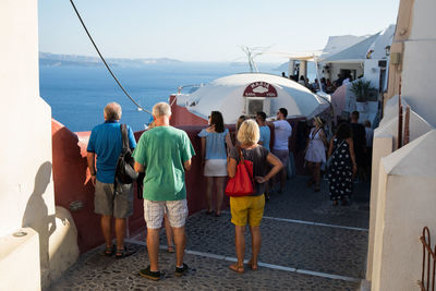 Rear view of people standing by sea against sky