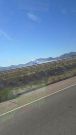 Road by mountains against clear sky