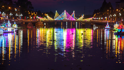 Illuminated buildings by river in city at night soc trang