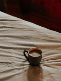 High angle view of coffee cup on bed