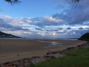 Scenic view of beach against cloudy sky