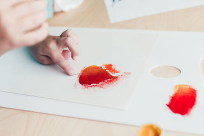 Midsection of woman holding heart shape on table