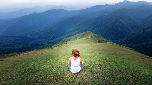 Rear view of woman sitting on mountain