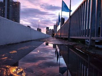 Bridge over canal by buildings against sky in city