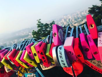 Close-up of love locks hanging on metal against sky