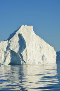 View of majestic iceberg in sea against sky