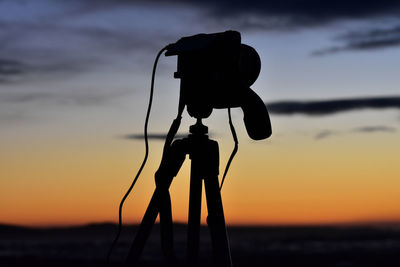 Silhouette camera against sky during sunset