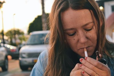 Close-up of mid adult woman smoking cigarette during sunset