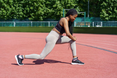 African american lady with long braids enjoys effective exercise for gluteal muscles on city stadium