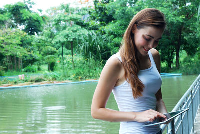 Beautiful young woman in lake against trees