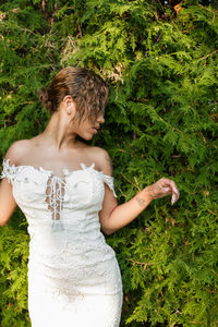 Young woman with white dress standing against tree