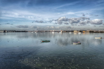 Sailboats moored in sea against sky