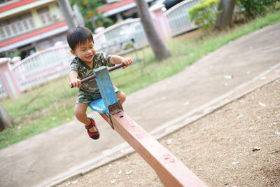 Cute boy playing on seesaw at playground