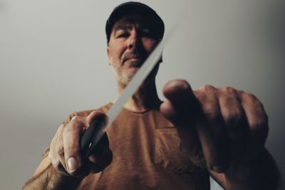 Low angle view of man holding knife against ceiling at home