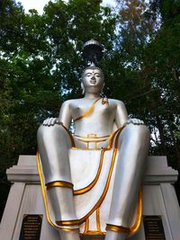 Low angle view of buddha statue against trees