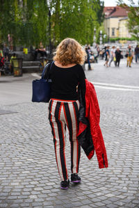 Rear view of woman standing on footpath in city