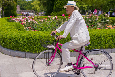 Side view of man riding bicycle on flowering plants