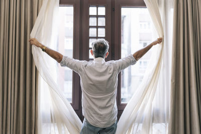 Rear view of man standing by window