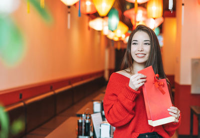 Beautiful young asian woman in red clothes with red gift bag celebrating chinese new year